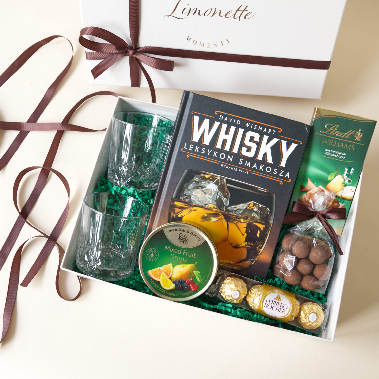 Zestaw Prezentowy Whisky Moments zawiera książkę z ciekawostkami na temat Whisky, dwie szklanki do whisky, landrynki o maku owoców i inne słodycze