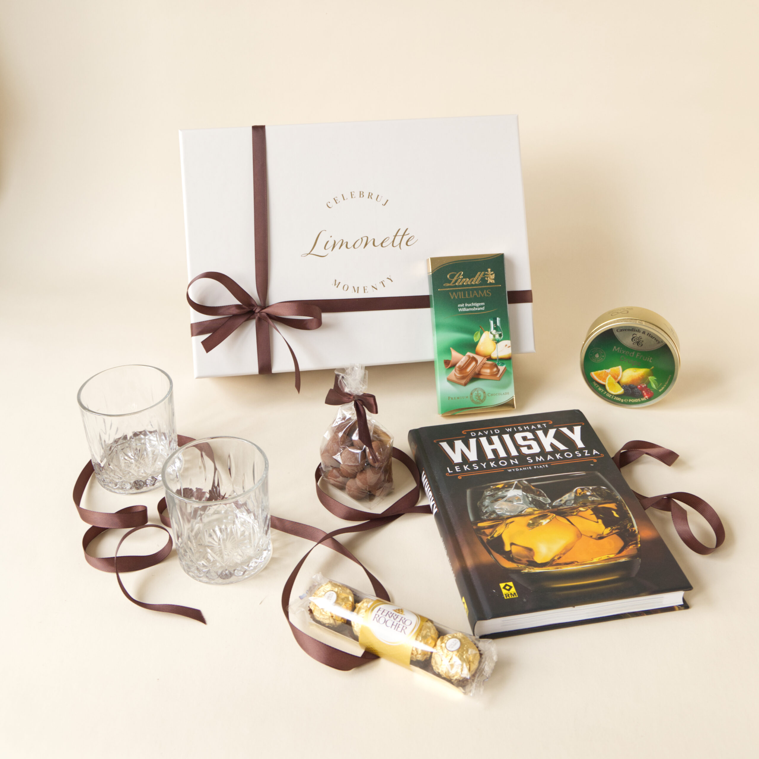 Zestaw Prezentowy Whisky Moments zawiera książkę z ciekawostkami na temat Whisky, dwie szklanki do whisky, landrynki o maku owoców i inne słodycze
